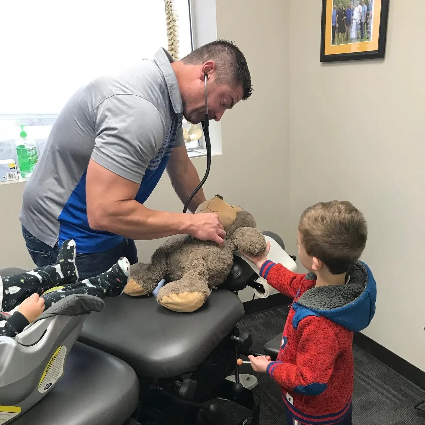 Dr. Adam Evans using a stethoscope on a young patient's stuffed bear at Columbia Valley Chiropractic Center
